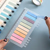 A hand is holding a transparent sheet of self-adhesive sticky notes with various pastel colored strips, showing the adhesive 