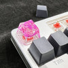 Translucent pink botanical resin keycaps and mechanical switches displayed on a keyboard layout.