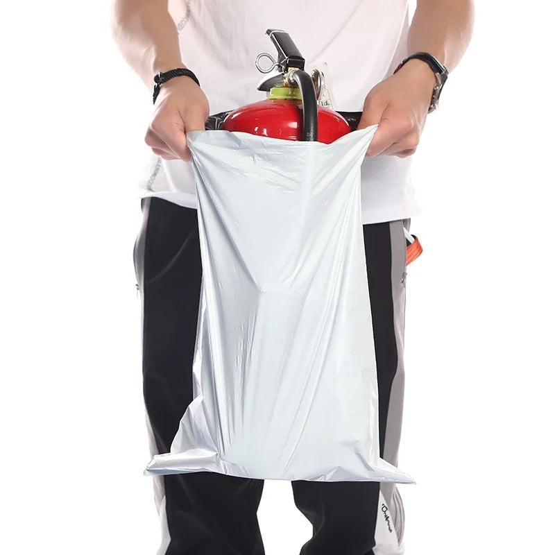 A person holds a clear plastic self-sealing mailing bag filled with red objects.