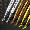 A collection of metallic brush marker pens in various gold and silver colors displayed against a dark background.