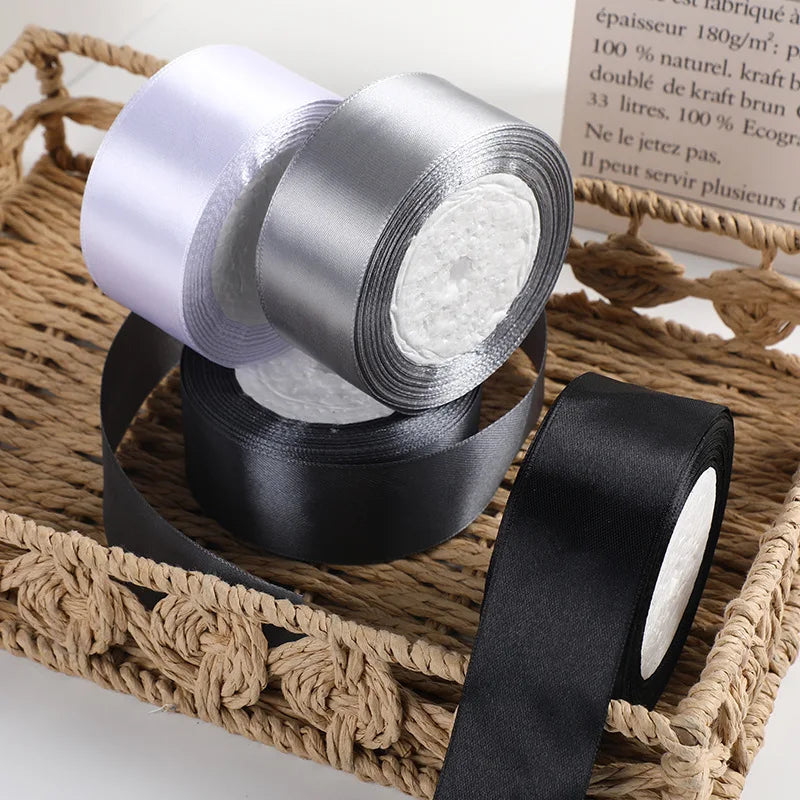 Rolls of satin ribbon in white and black wrapped on a woven basket