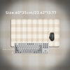 A beige plaid pattern non-slip mouse pad with a silver keyboard placed on top.