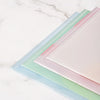 A set of four transparent document pouches in pastel colors, including pink, mint green, and light blue, laid diagonally on a