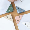 A collection of colorful triangle folder clips or document holders in green, blue, and pink resting on a wooden surface.