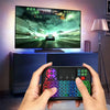 يد تمسك بلوحة مفاتيح وماوس لاسلكية سوداء مزدوجة النمط RGB أمام شاشة كمبيوتر.