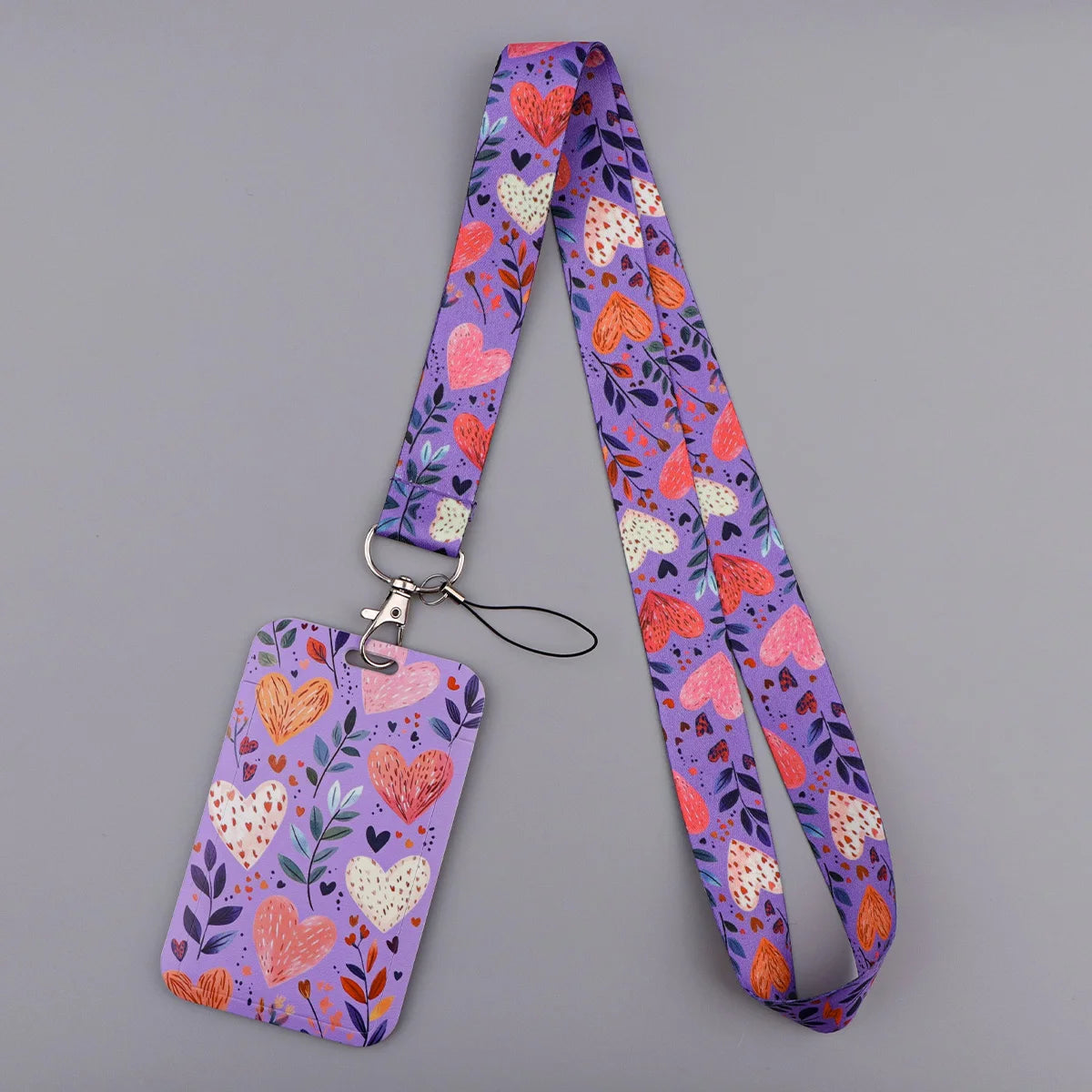 A purple lanyard featuring a pattern of pink and white heart-shaped floral designs.