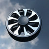 A close-up view of a black and silver metal fidget spinner against a cloudy blue sky.