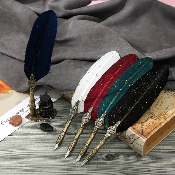 A set of retro calligraphy feather dip pens in various colors resting on a gray cloth and a wooden box.