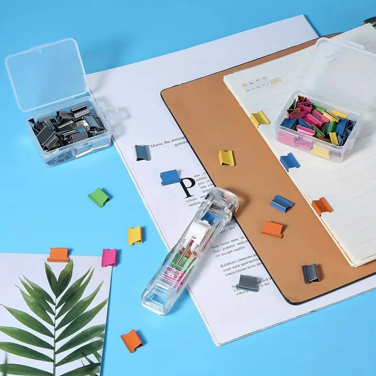 A set of professional clip pusher staplers and related accessories displayed on a desk with paper.