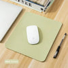 A mint green mouse pad with an Apple mouse and a pen resting on a wooden surface.