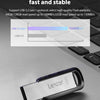 A silver Lexar USB flash drive is shown resting on a dark gray laptop surface.