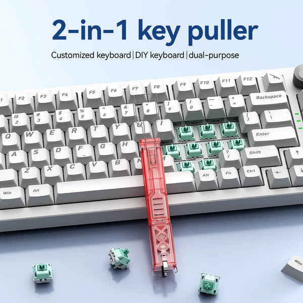 Gros plan d'un outil tire-clés rouge 2-en-1 avec divers composants de clavier verts et blancs sur une surface.