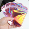 A hand holds a stack of iridescent self-sealing jewelry pouches with a resealable zip lock.