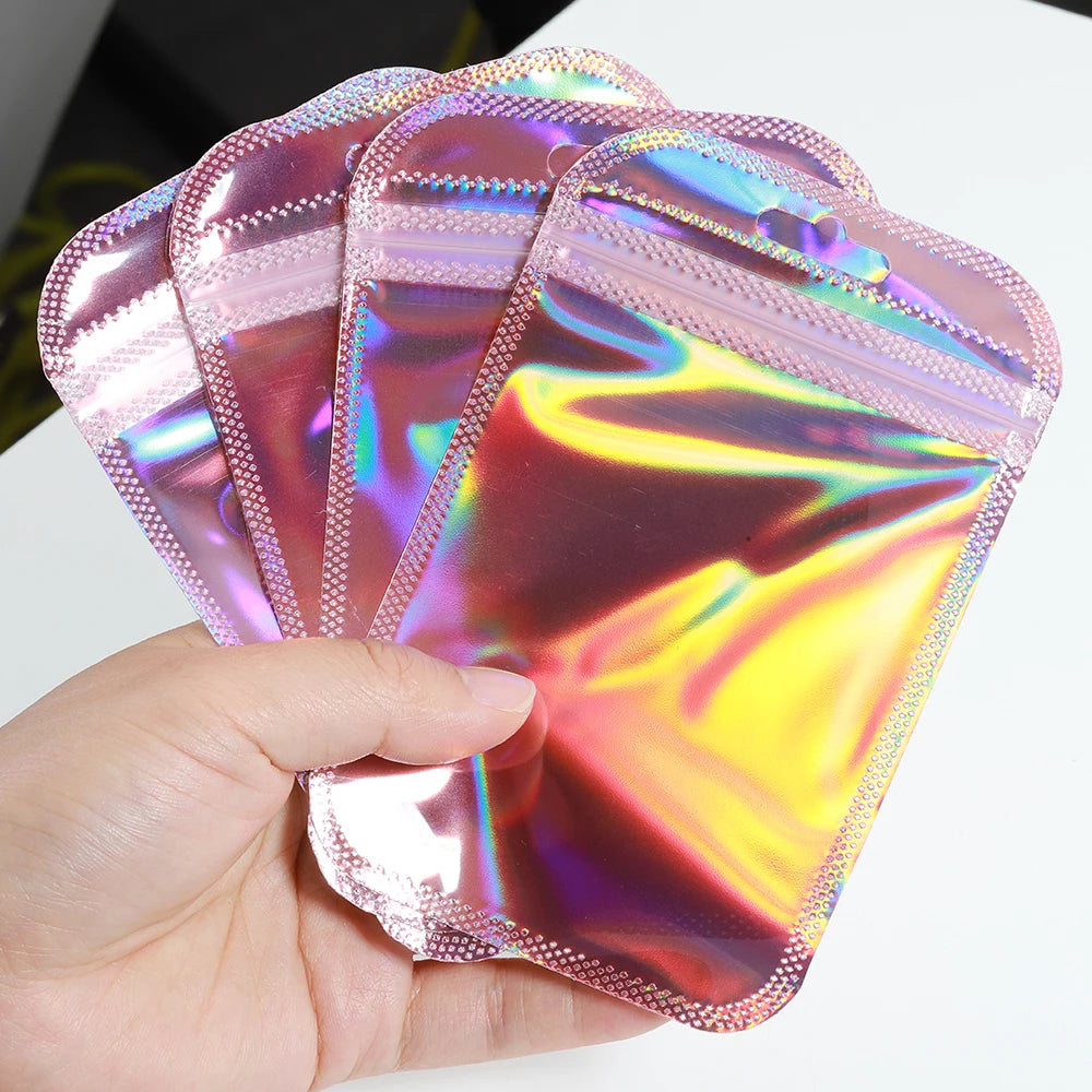 A hand holds a stack of iridescent self-sealing jewelry pouches with a resealable zip lock.