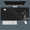 A black gaming mousepad with a silhouette of a figure and a white keyboard and mouse placed on it.