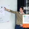 A man points to a magnetic whiteboard displaying various documents and graphs, demonstrating a stronger magnetic force.